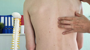 a doctors fingers placed on a persons spine