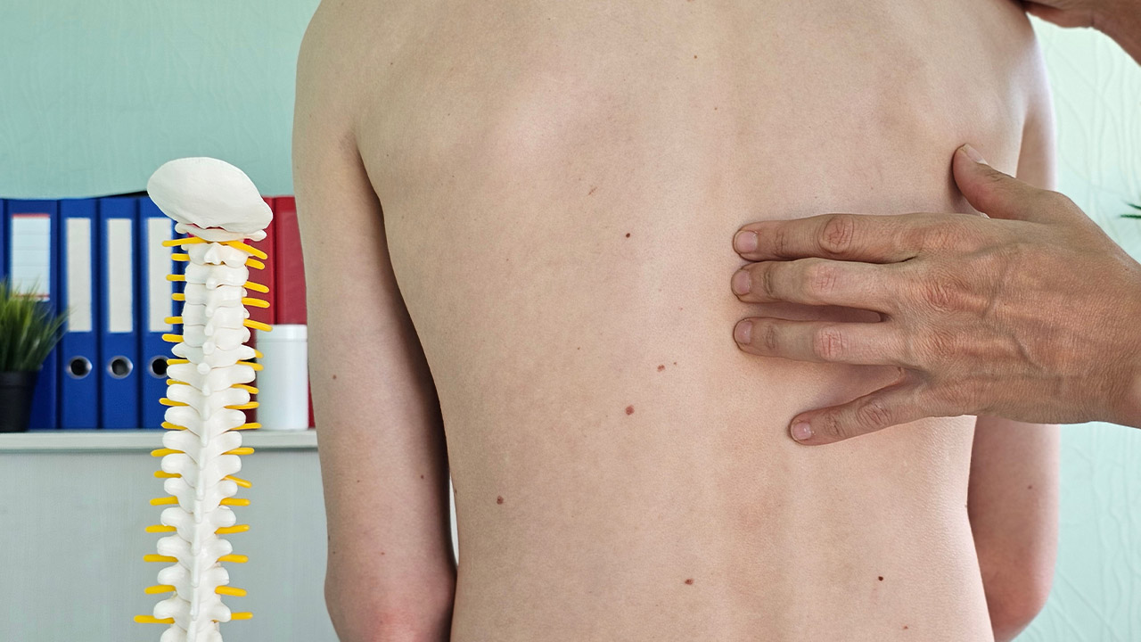 a doctors fingers placed on a persons spine